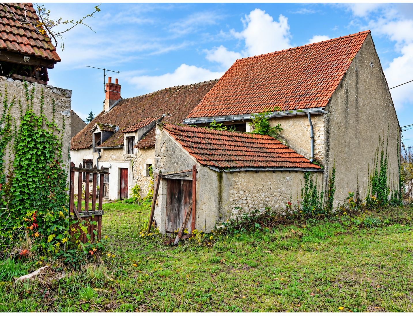 Une vieille ferme en pierre aux toits de tuiles, avec une grange et un portillon en bois, entourée d'herbe et de lierre.